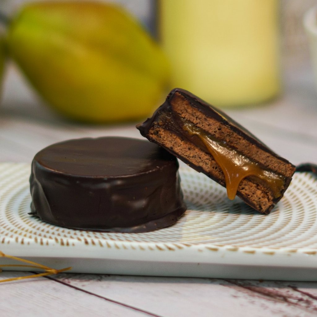 Chocolate-dipped cookie with caramel filling on a white plate